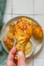 A person presents the best air fryer chicken drumsticks on a plate.