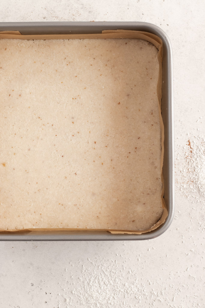 The coconut centre pressed flat onto the base in the cake tin.