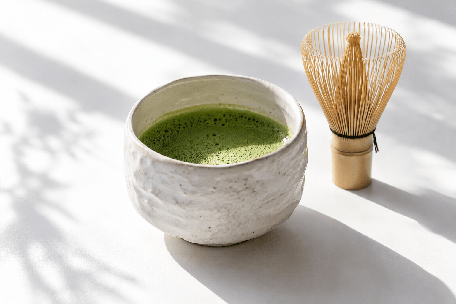 白い茶碗に点てた抹茶と竹の茶筅