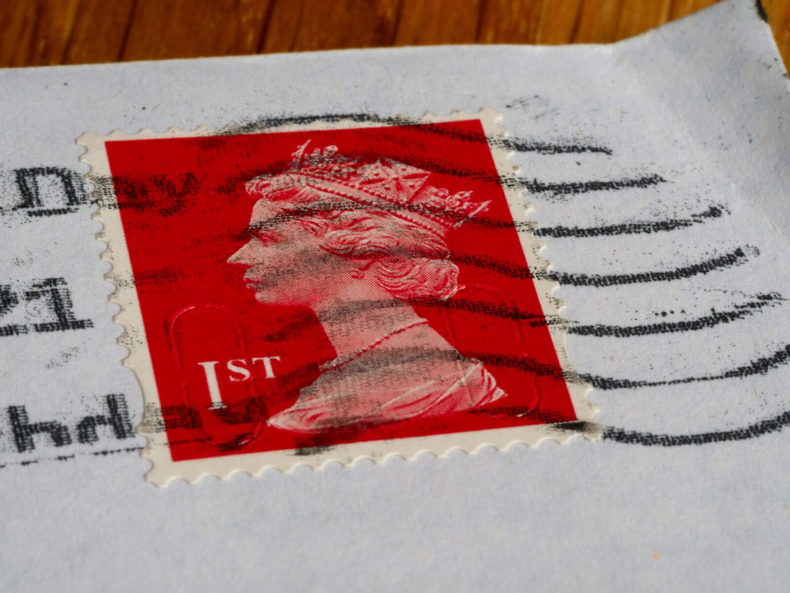 High-quality close-up of a red British postage stamp with postal markings, showcasing the queen's profile.
