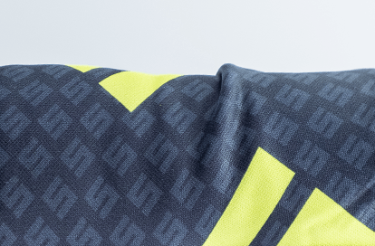 Close-up of dark blue patterned fabric with bright neon yellow geometric shapes.
