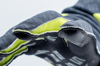 Close-up of a black protective glove with neon yellow lining, reaching forward toward the camera.