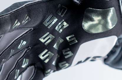 Close-up of a black cycling glove showing grip studs and logo pattern on the palm