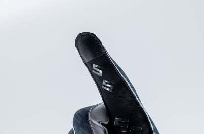 Close-up of a black sports glove fingertip with logo on a light gray background