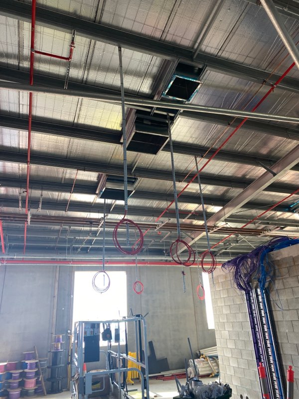 Red fire services pipework and cabling installed at ceiling level on a commercial site