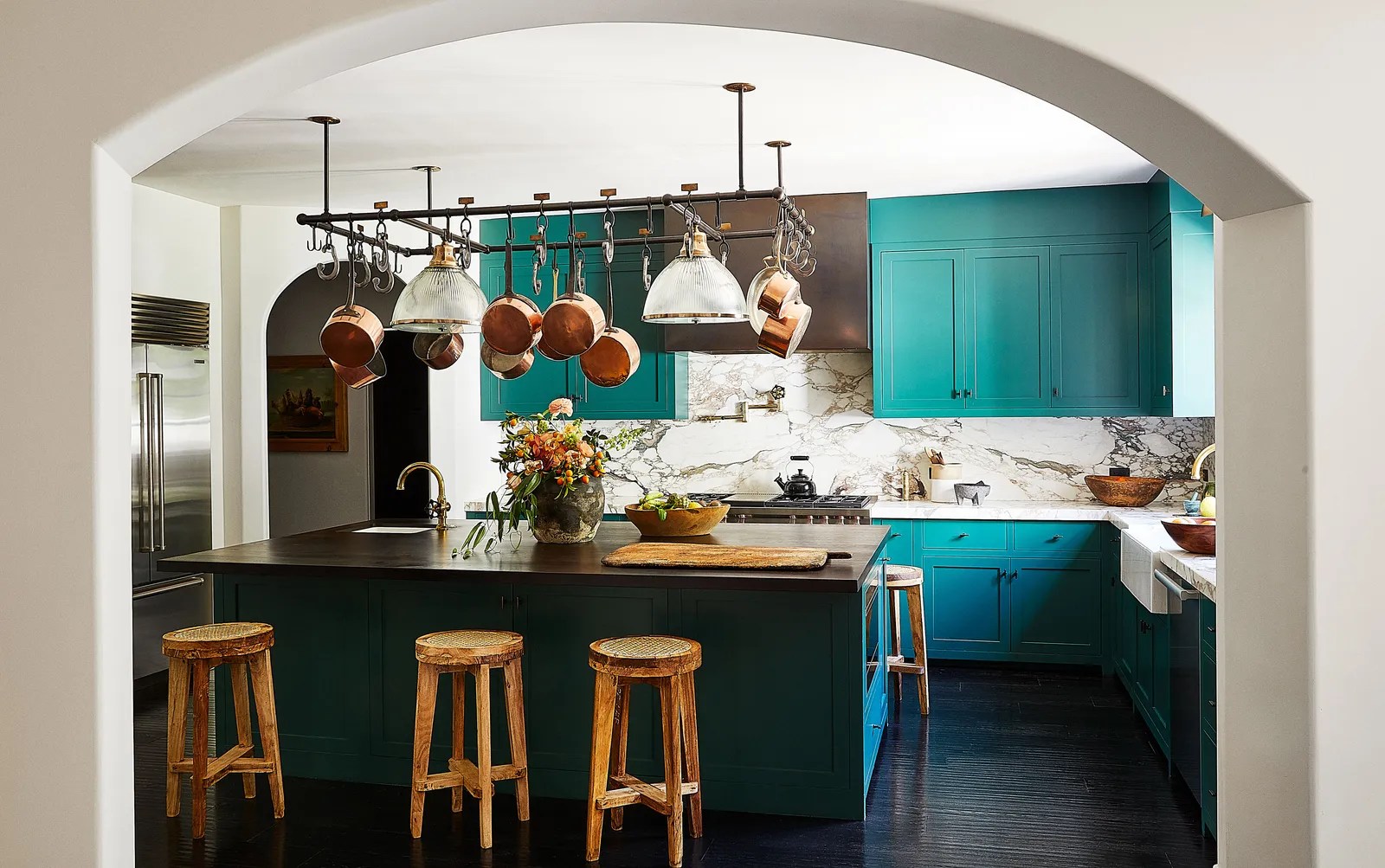 The kitchen cabinets are painted in a Benjamin Moore teal; Waterworks fixtures; Pierre Jeanneret teak stools from Galerie Half. William Abranowicz