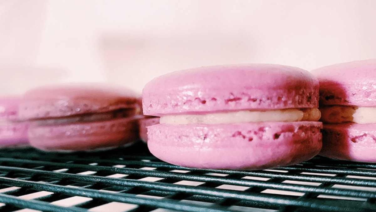 Pink macarons cooling on a wire rack tray.