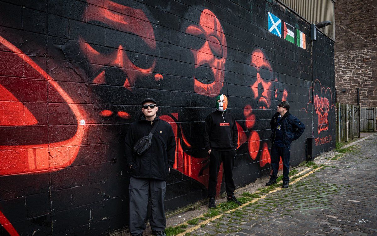The band in front of a Kneecap Fenian mural in Dundee, Scotland. Photo: Kneecap