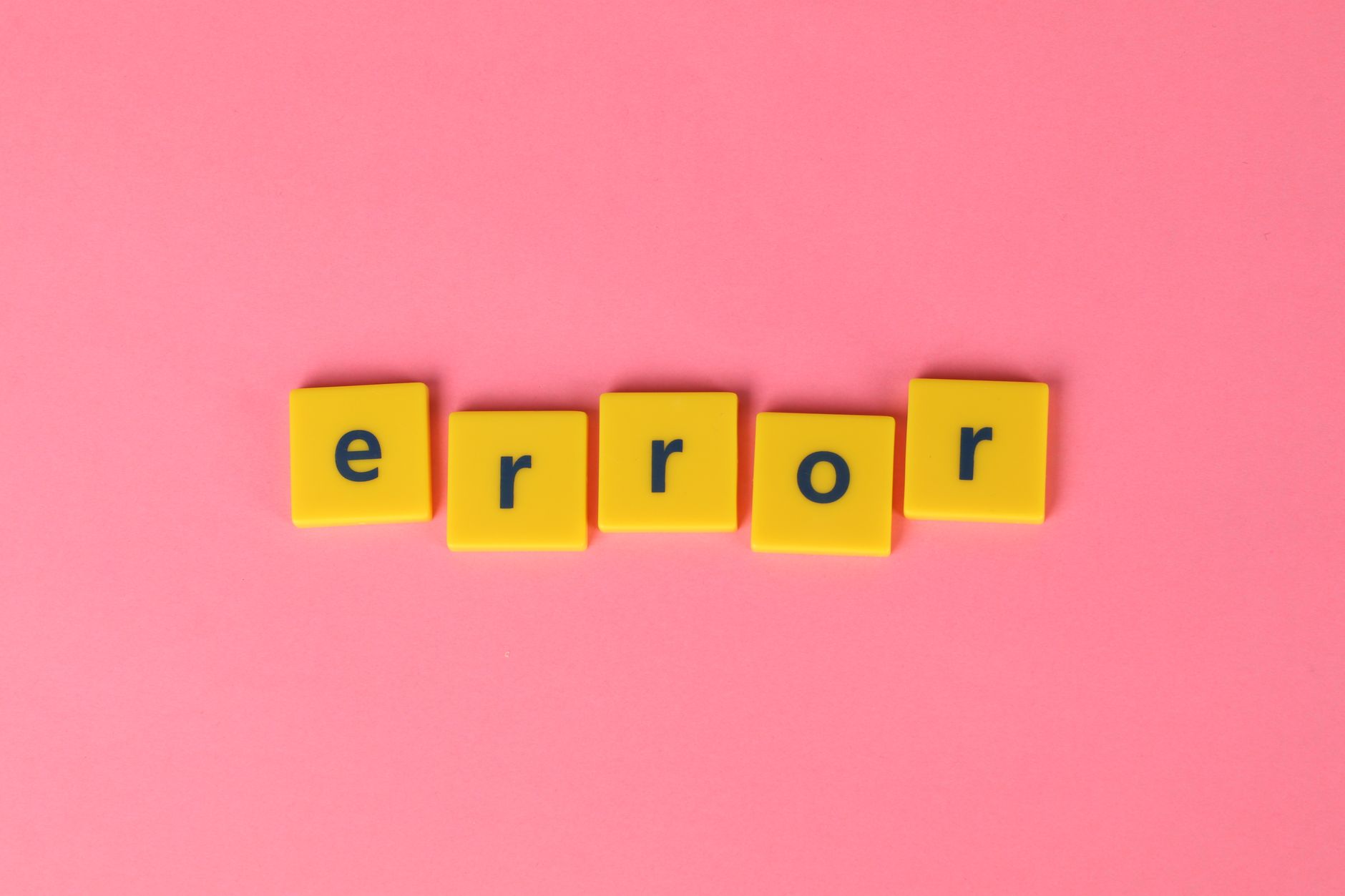 yellow scrabble tiles spelling out Error on a pink background