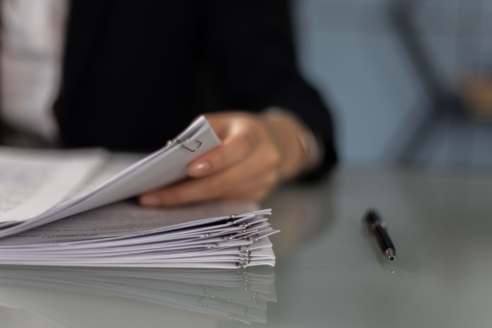 close up shot of a person holding a paperwork beside a pen