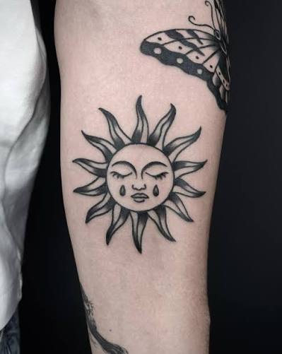 black & grey traditional (old school) tattoo of sun on the forearm