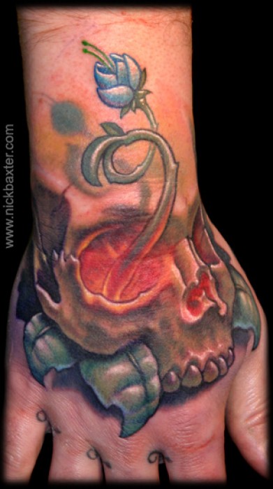 Tatuaje De Una Calavera En La Mano Con Una Flor Saliendo Del Ojo