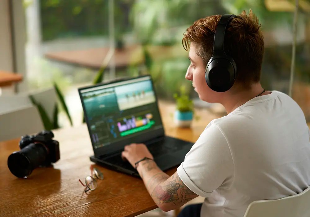 A sole trader podcaster editing some audio on his laptop.