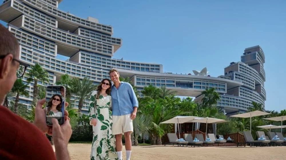 A visitor photographs a couple on the beach at Atlantis, The Palm, one of the hotels covered by A Dubai Invite perks