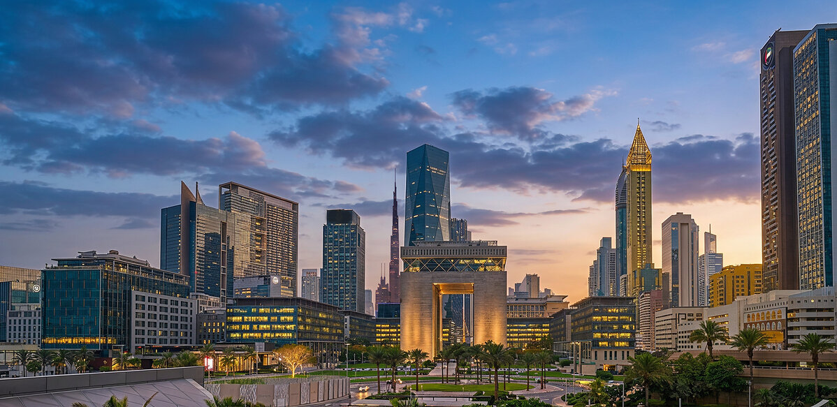 DIFC financial district in Dubai at dusk with the Gate Building and Burj Khalifa