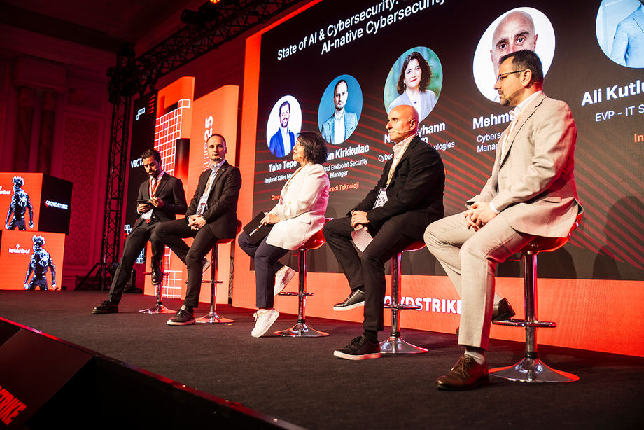 CrowdStrike CrowdTour panel speakers on stage, AI-native cybersecurity branding on the screen behind them