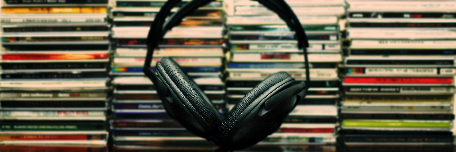 Black headphones in front of stacked compact discs