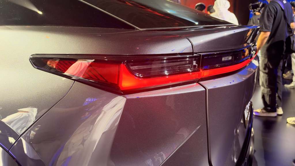 Close-up view of the rear of a modern car, showcasing sleek taillights and a sporty spoiler in a showroom setting.