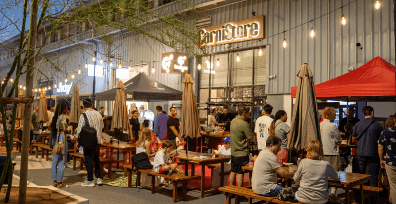 People gather at Alserkal Avenue outdoor tables beneath evening string lights