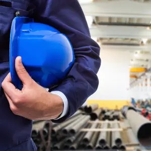 Man in warehouse holding blue hardhat under his arm