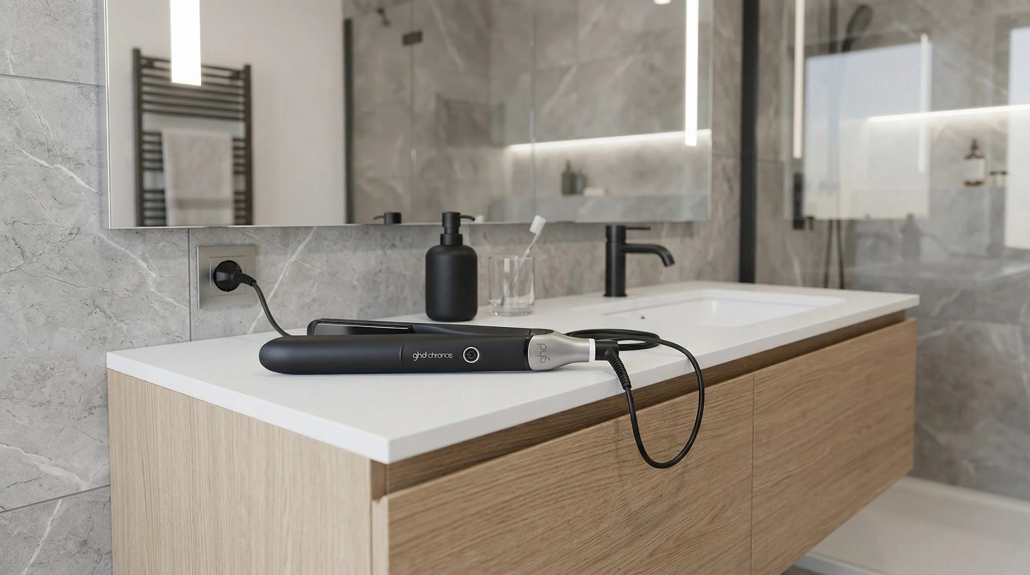 Un cuarto de baño moderno, en primer plano una plancha del pelo GHD Chronos sobre el lavabo.