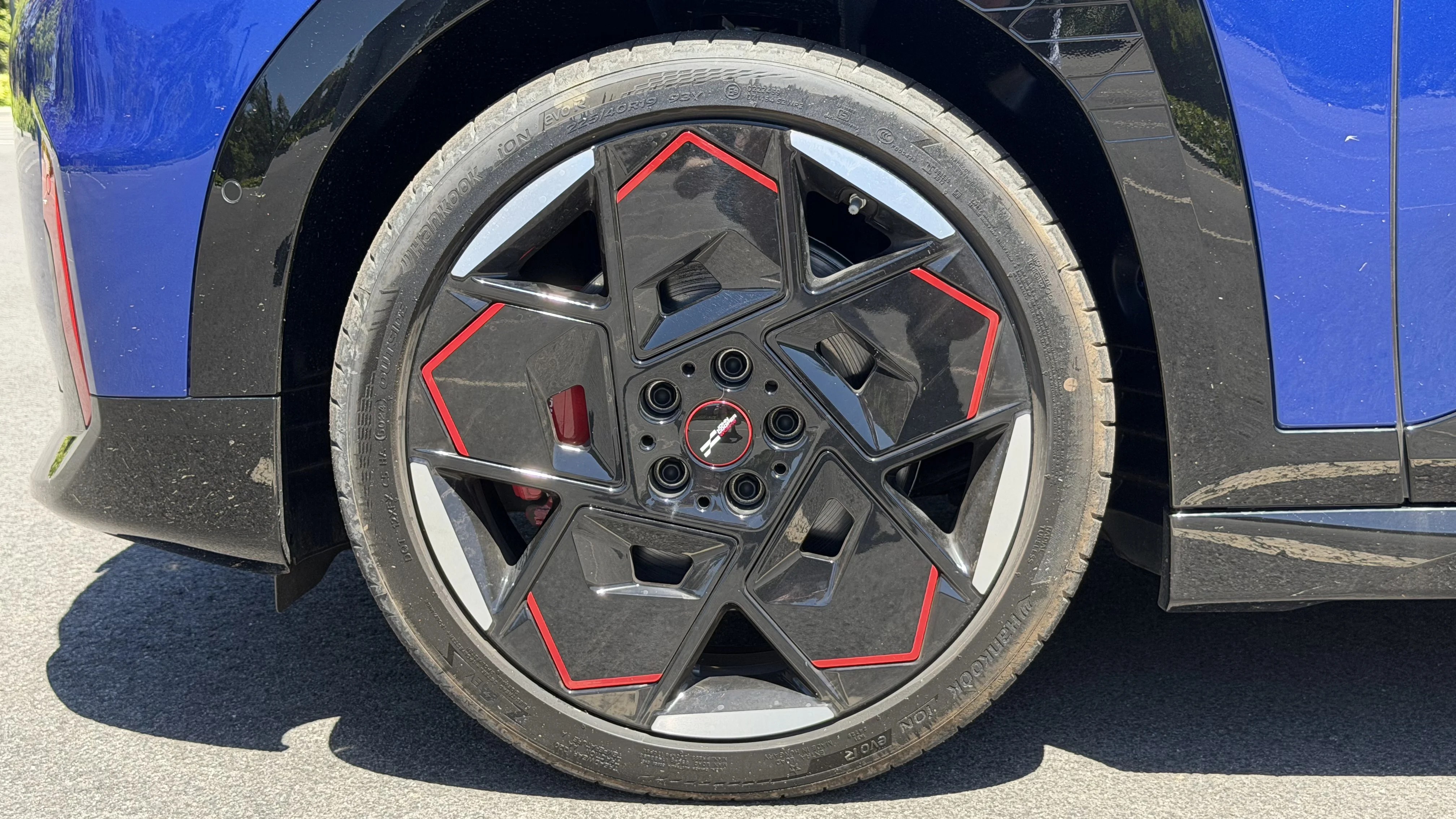 Front wheel and tyre of 2026 Mini Aceman JCW, black geometric alloy with red trim and visible red brake caliper
