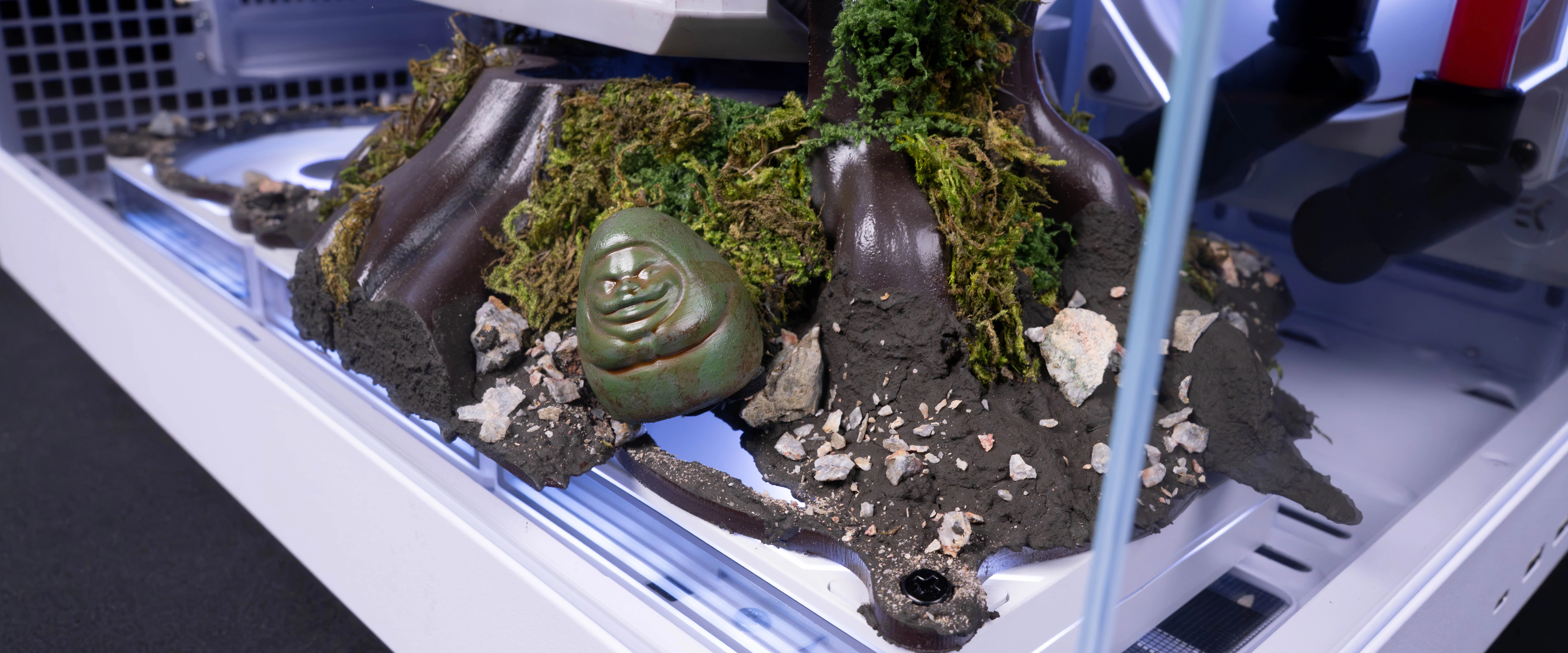 Close-up of the sculpted tree base with moss-like decoration, rocks and a small green ornament