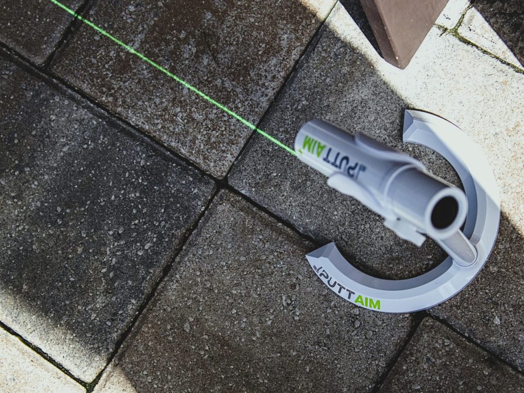 PuttAIM+ with laser showing on pavers in daytime -- Techigar