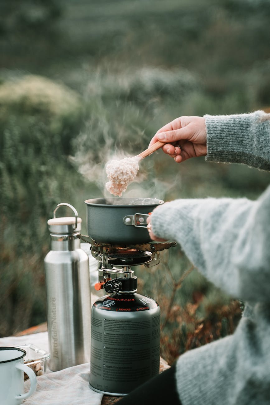 a person cooking oatmeal using portable stove