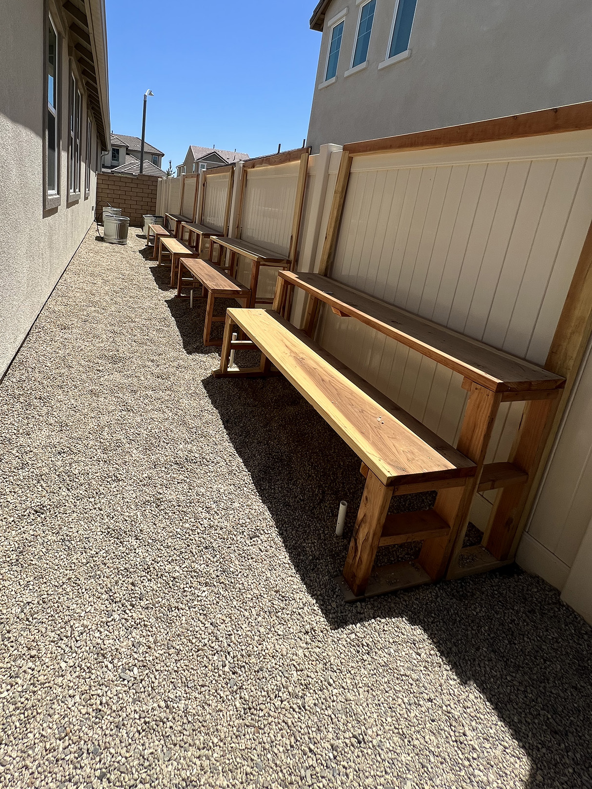 Shot of granite floor, wooden bench pieces, and white fencing.