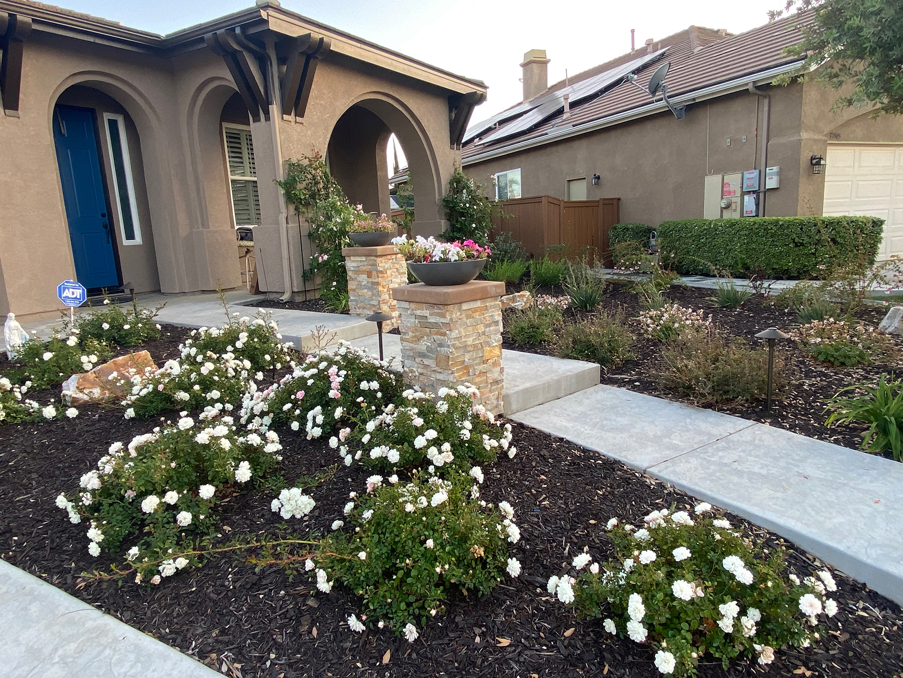 Shot of mulch planters, concrete stairs, and stone columns.