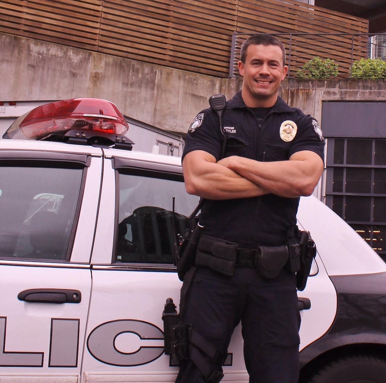 police officer standing by his car smiling