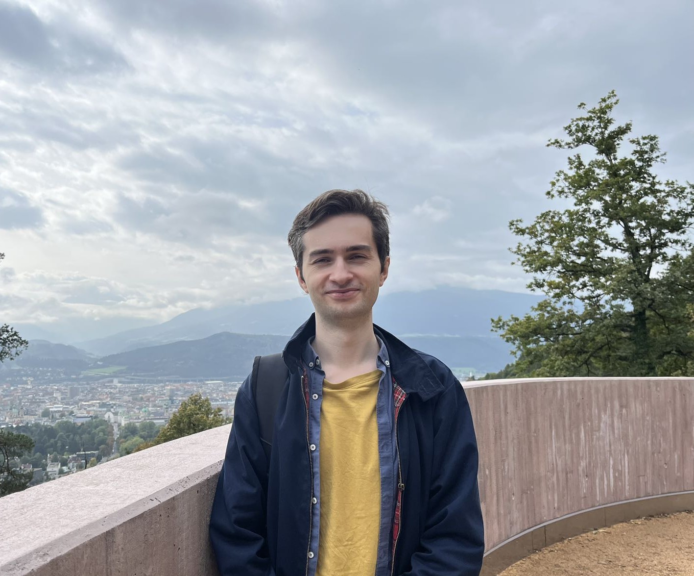 Image of Tom on travels in Austria. Some mountains (and clouds!) in the background.