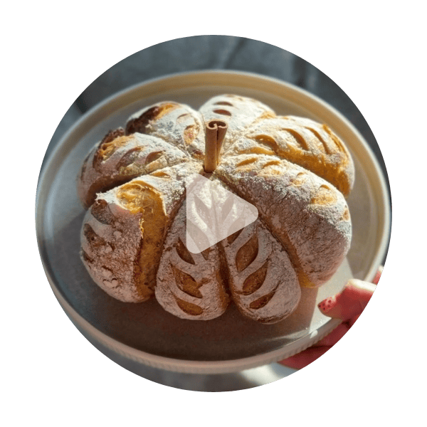 Pumpkin shaped sourdough loaf with a cinnamon stick stem, scored with leaf patterns