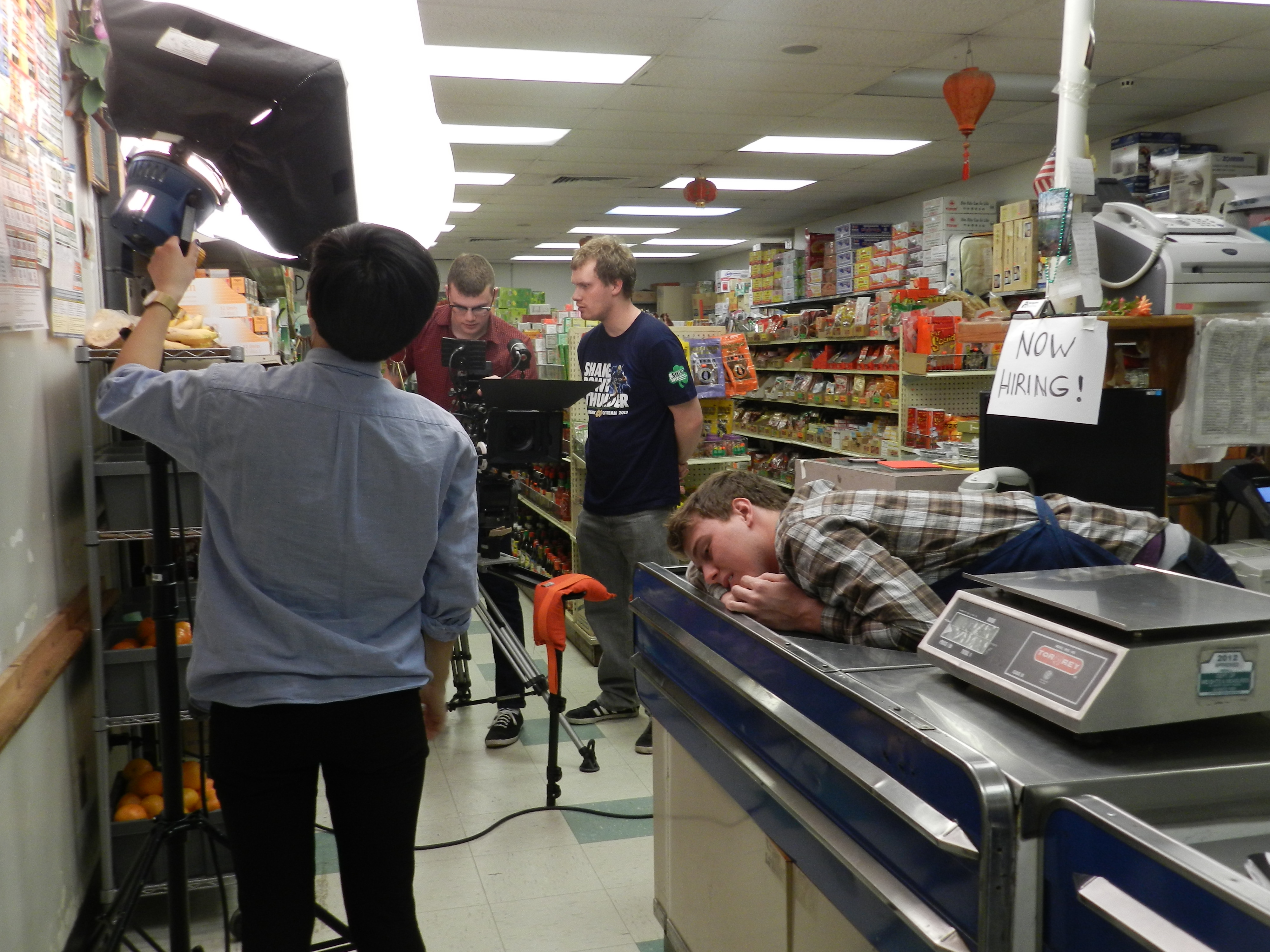 The directors and crew set up a scene while the tired actor waits, their shoot going late into the night and into the next day. Shooting that day had about 7 or 8 different set ups, each needing rearrangement of lights, camera, tripod, actors, and audio that could take from 10 to 20 minutes to set up.