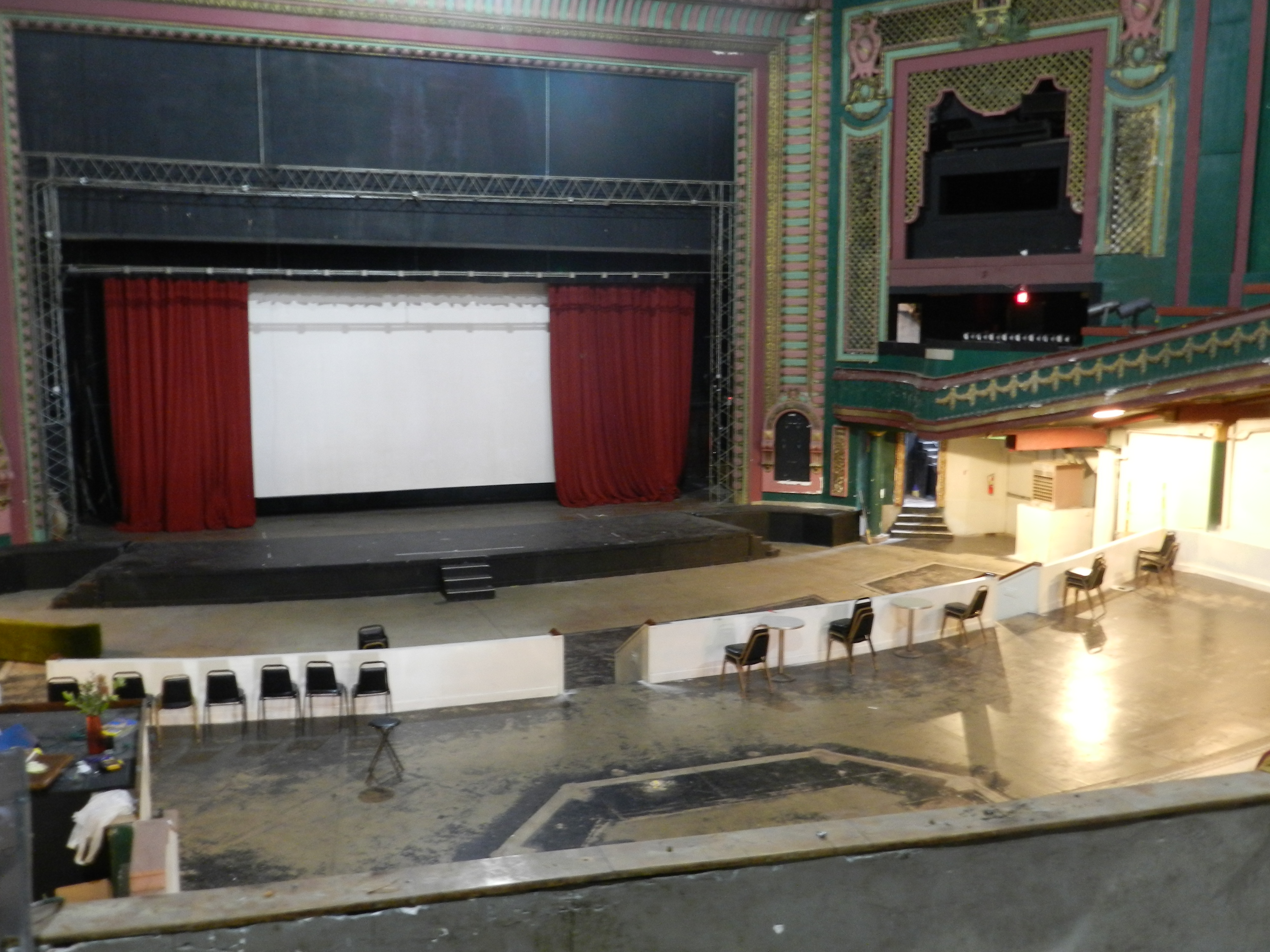 The stage was likely meant for movie theater viewings and vaudeville acts when built in 1919, reminiscent of the grand theaters of the 20s, but has since been used as a Christian space, a bar, a meeting space, and a music venue.