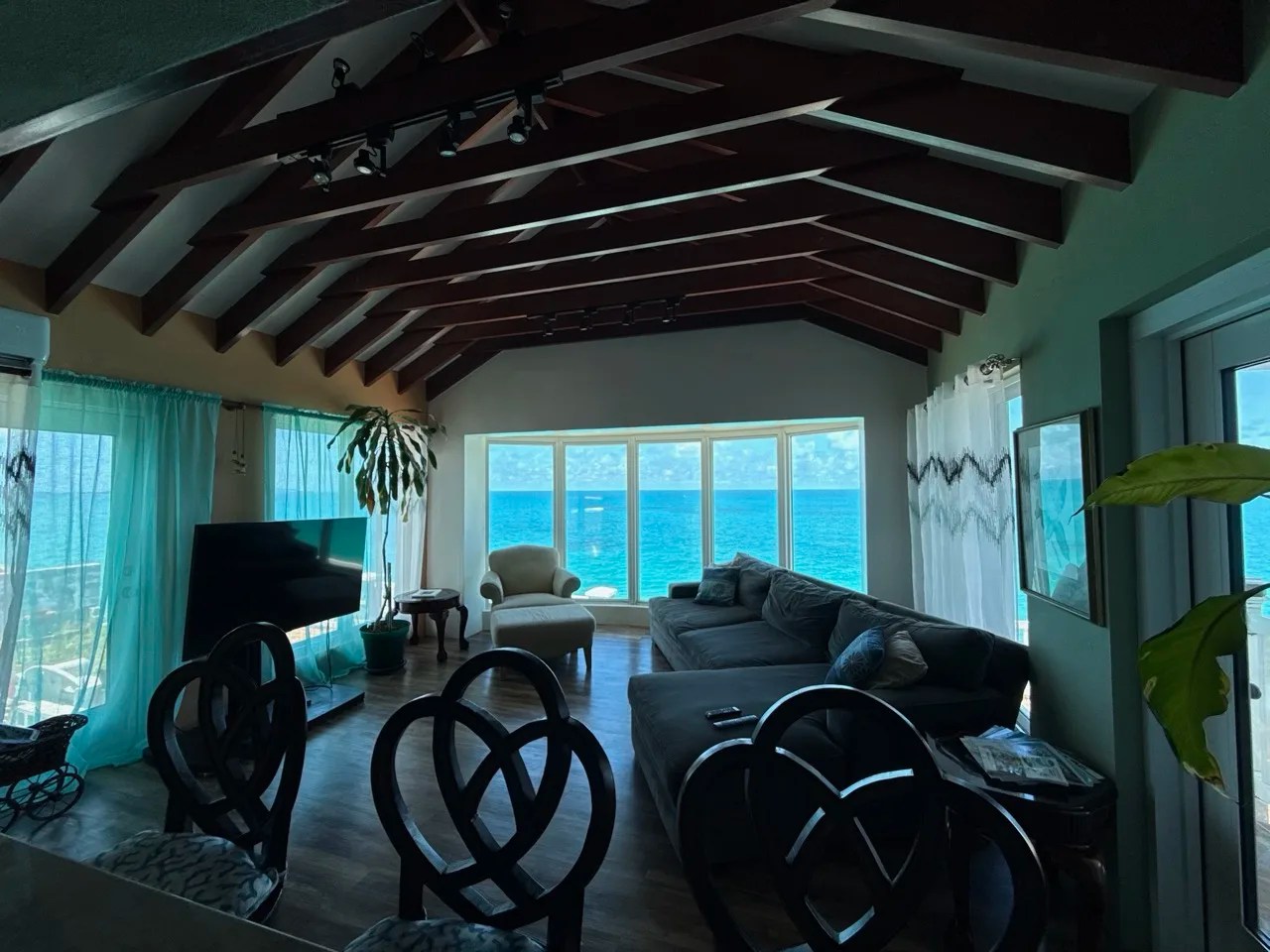 living room of our waterfront rental home in devonshire, bermuda, with a wood-beamed ceiling and windows looking out to sea