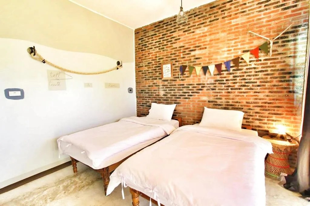 twin room with a red brick wall and colorful bunting at above the sea maesariang on the mae hong son loop