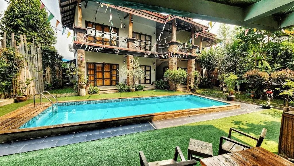 swimming pool in a garden in front of the two-story guesthouse at above the sea maesariang in mae sariang, thailand
