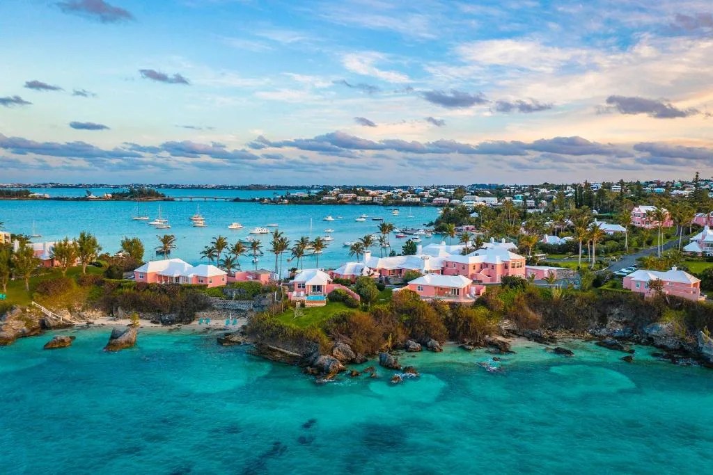 aerial view of the pink cottages of cambridge beaches resort on a peninsula surrounded by turquoise water in somerset, bermuda