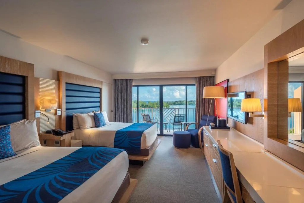 guest room with two beds and a balcony overlooking the bay at grotto bay beach resort, bermuda