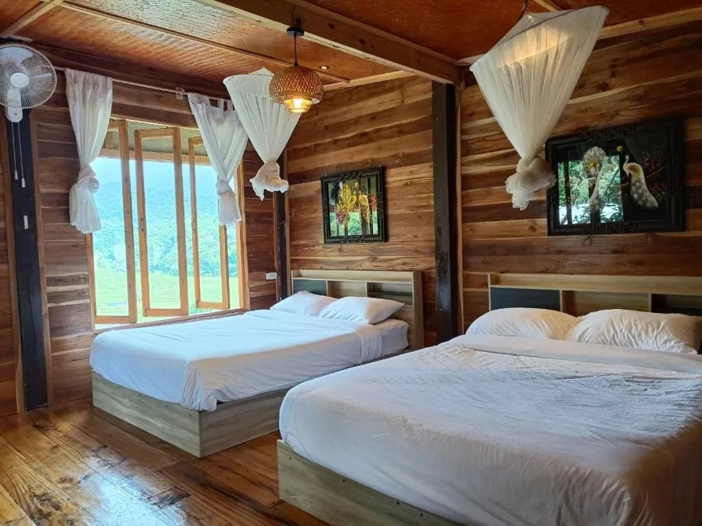 wooden bedroom with two double beds, mosquito nets and windows facing the mountains at motho homestay on doi inthanon