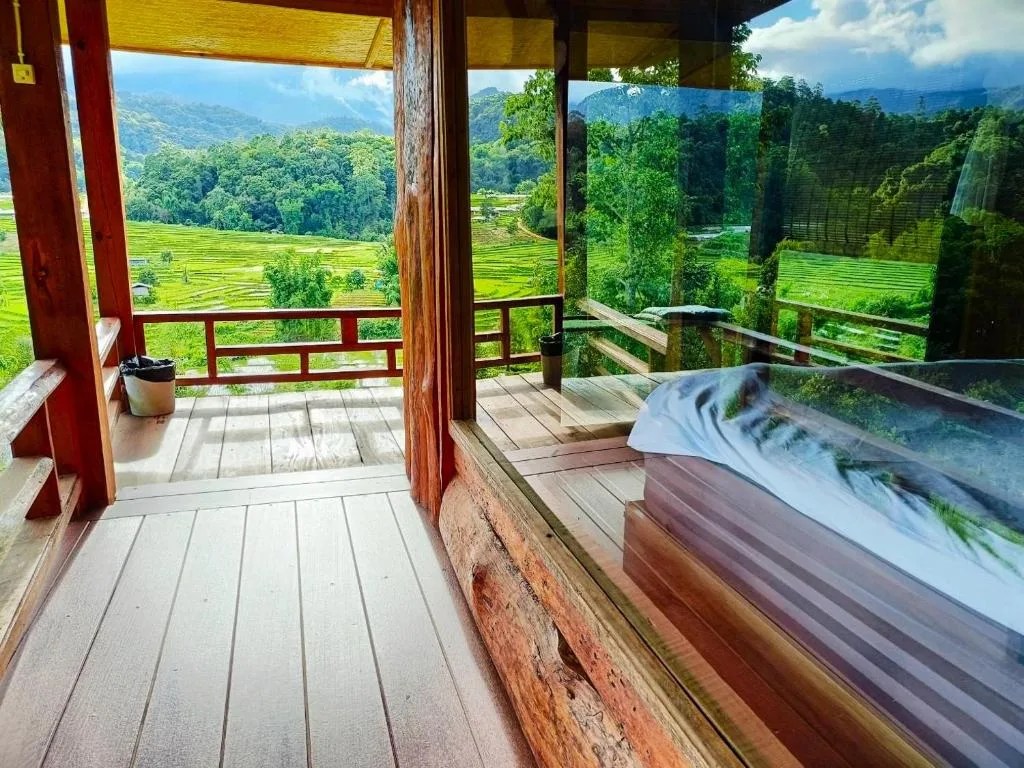 wooden balcony at motho homestay overlooking bright green terraced rice fields and the mountains of doi inthanon, thailand