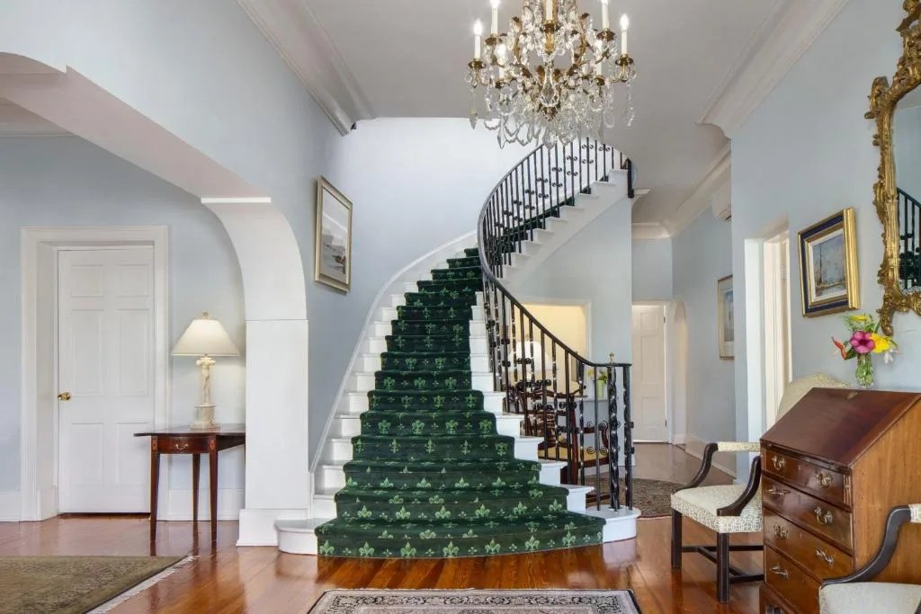 entrance hall with a curved staircase and crystal chandelier at oxford house in hamilton, bermuda