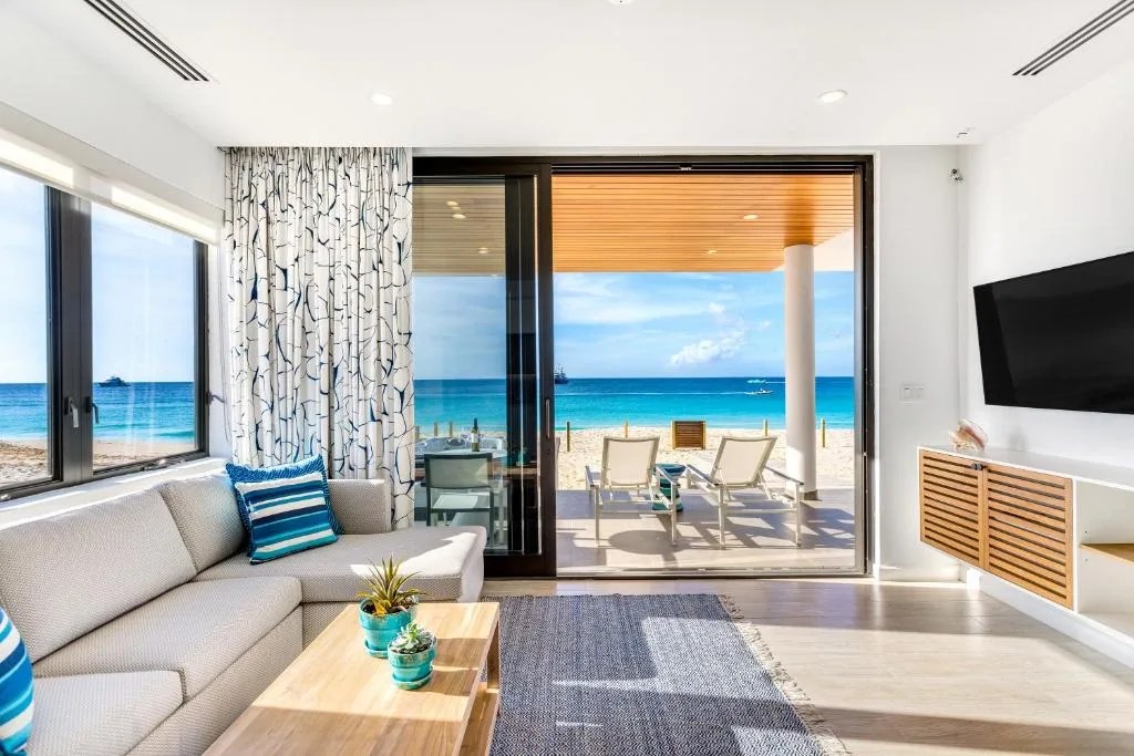 living room of hotel room at the tranquility beach anguilla resort, with sliding doors opening onto the beach