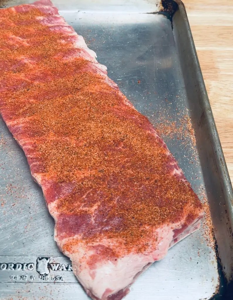 seasoning on rack of st. louis style ribs on a sheet pan