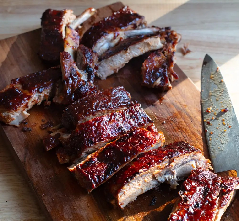 st louis style bbq ribs cut in pieces on a cutting board with a knife on the side