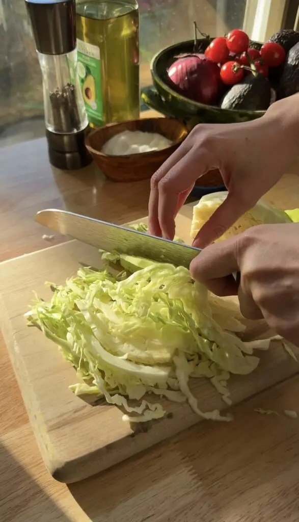 cutting cabbage with knife on cutting board