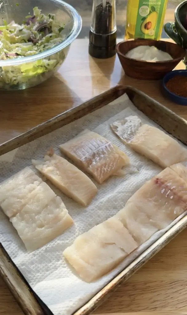paper towel lined sheet pan with raw fish filets