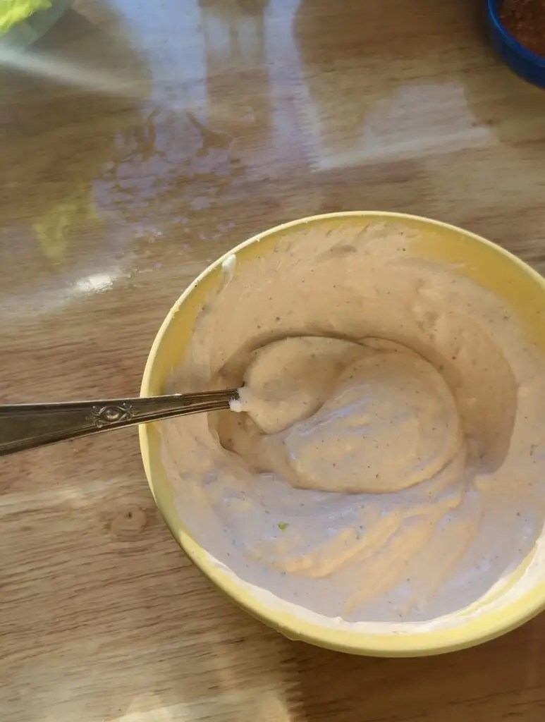 yellow bowl with sour cream sauce with a spoon in it